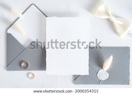 Wedding invitation card template. Flatlay blank paper card, grey envelopes, goled rings on white background. Vintage style. Top view.
