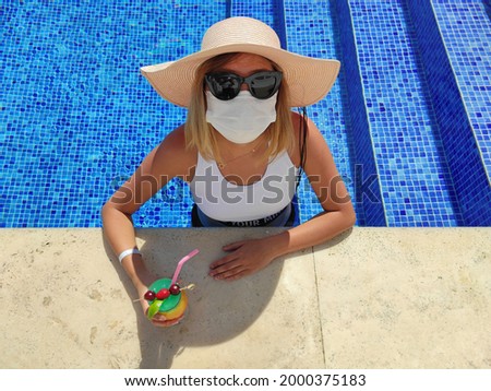 Vacationing woman wearing medical protective face mask on swimming pool
