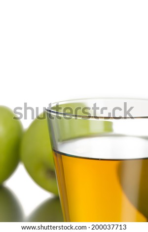 Glass filled with juice in front of two green apples close up