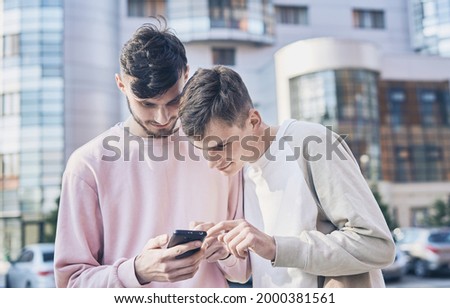 two friends with smartphones talking and walking