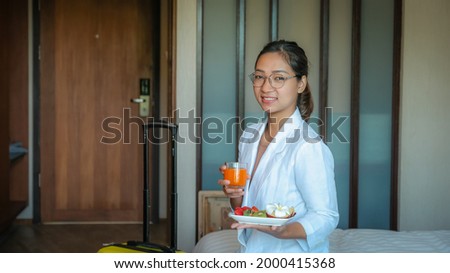 Picture of businesswoman eating fruits and drink orange juice on the bed in the luxury hotel room, healthy food concept.