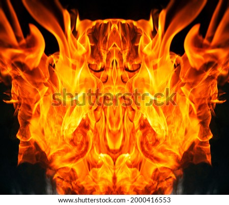 The fiery face created by the tongues of fire resembles the tales of legends and beliefs in the underworld and devils, red crimson orange colors and black smoke soot