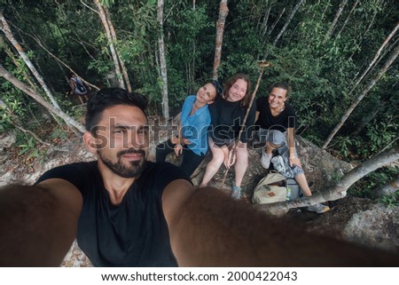 Selfie of the company on vacation in a hike in the rainforest. Portrait of a young guy and girls having a rest at a halt in the mountains in the jungle