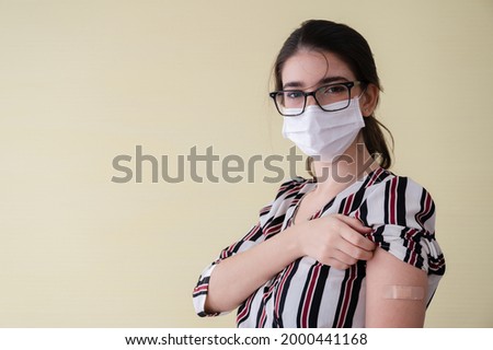Young women wearing masks standing show plaster bandage at the shoulder. After vaccine protection coronavirus 19 for immunization. Concepts to prevent the spread of COVID-19.