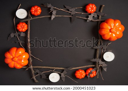 Halloween background, orange decorative plastic pumpkin black paper bat dry branch stick square frame  black cardboard Thanksgiving greeting card pattern