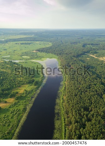 Beautiful summer landscape with a drone on an oblong lake, forest, sky. Vertical photo