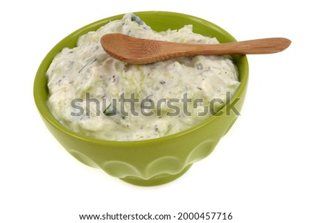 Bowl of tzatziki with wooden spoon close-up on white background