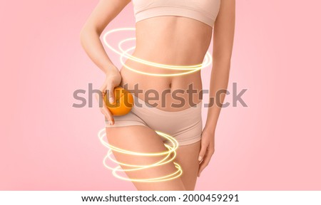 Young woman with orange fruit on color background. Concept of cellulite Royalty-Free Stock Photo #2000459291