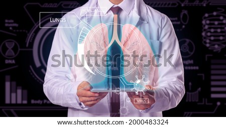 Male doctor holding tablet computer and virtual screen with picture of lungs on dark background