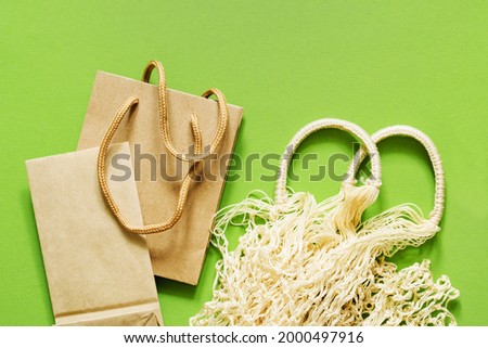 Reusable shopping bag and paper packaging on a green background close-up, top view. No plastic, no waste, biodegradable packaging. Environment protection
