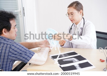 Female doctor talks and analysis in patient hospital. Woman Caucasian doctor check up the broken bone at man's right arm with bandage.