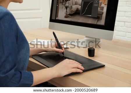 Professional retoucher working on graphic tablet at desk, closeup
