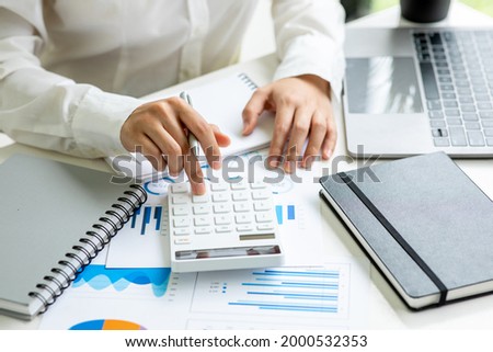 Financial Business women  use calculator analyze the graph of the company's performance to create profits and growth, Market research reports and income statistics, Financial and Accounting concept.