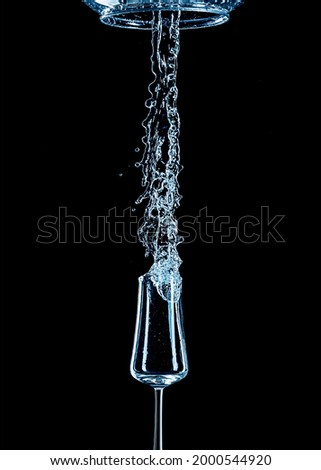 Water splash with inverted glass and black background.