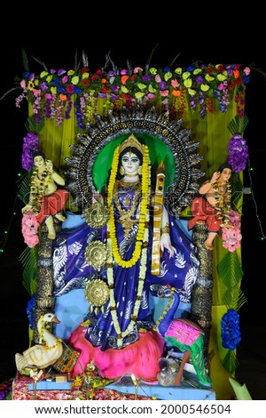 Idol of Goddess Saraswati being worshipped, at night. Colorful light on Hindu goddess. Howrah, West Bengal, India. Vertical image.