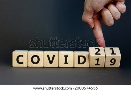 Symbol of covid-19 pandemic in 2021 year. Businessman turns wooden cubes and changes words 'covid-19' to 'covid-21'. Beautiful grey background, copy space. Medical, 2021 year covid-21 concept.