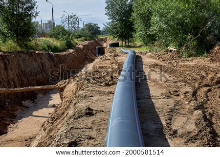 Civil engineering. Plastic water pipe lies next to the trench for installation. Royalty-Free Stock Photo #2000581514