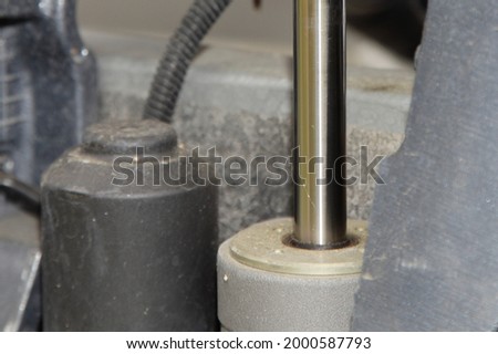 Motor boat outboard motor lower unit power trim and tilt cylinder with a chrome rod and hydraulic pump closeup Royalty-Free Stock Photo #2000587793