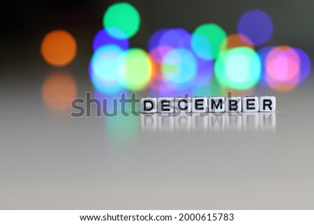 The DECEMBER text on white cubic blocks. The letters are written on the cubes in black letters highlighted on the glass surface. DECEMBER, text for your design.
