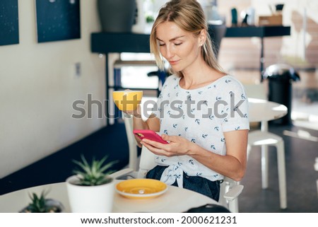 Young beautiful blonde woman smiling uses social media in a mobile phone.