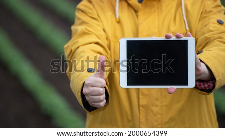Farmer showing tablet, blank screen and holding thumb up as ok sign in field