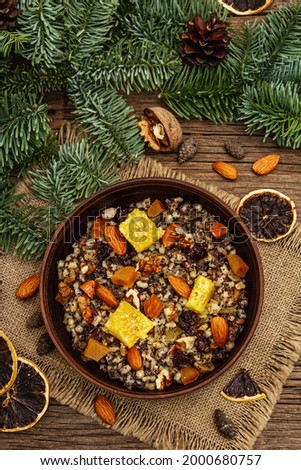 Traditional Christmas dish Kutya. Slavic sweet food with dried fruits, poppy seed and nuts. Wheat porridge in East European, Russian, Ukrainian countries. Old wooden boards background, top view