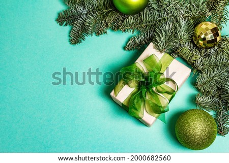Christmas decoration background. Evergreen fir tree branches, New Year toys, gift box on a turquoise matte background, top view