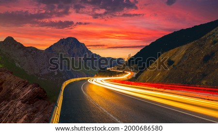 highway view at sunset. car lights form long colored lines on the highway. road view through mountains and colorful sunset view. European highways and mountains. Bavaria, Germany. Royalty-Free Stock Photo #2000686580