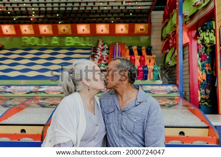 Happy senior couple kissing by a game stall