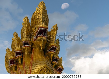Thai dragon or Naga isolated on blue sky with clouds and moon are background, Selective focus. King of Naga statue symbol of faith in Buddhism, can be seen in every temple in Thailand.