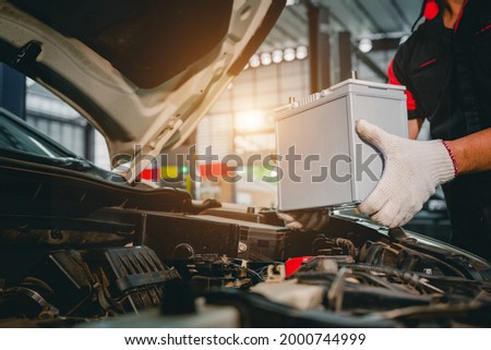 Close-up of a car mechanic in a service center picking up a new battery to replace the car. for cars that use the service Replace the battery at the store Royalty-Free Stock Photo #2000744999