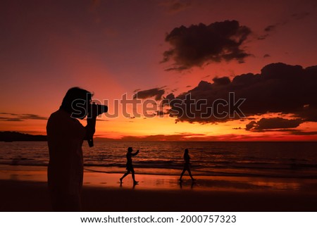 Silhouette of A man taking picture of beautiful sunset on the  sea beach as summer