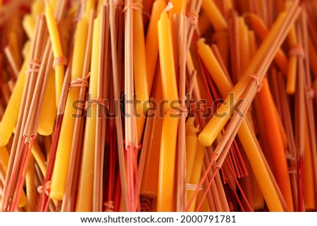 A pile of incense and yellow candles which tied with rubber band