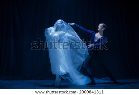 Graceful balerina in image of ghost bride with patner in art ballet performance isolated over dark background. Concept of love, relationship, beauty, art and theater. Copy space for ad.