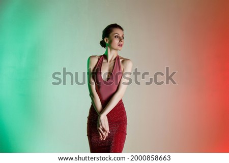Colored background, neon lights, studio shot. Portrait of a young elegant brunette woman in a beautiful dress. Beauty salon concept