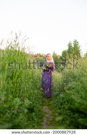 portrait of a girl in a blooming field in the sun at sunset