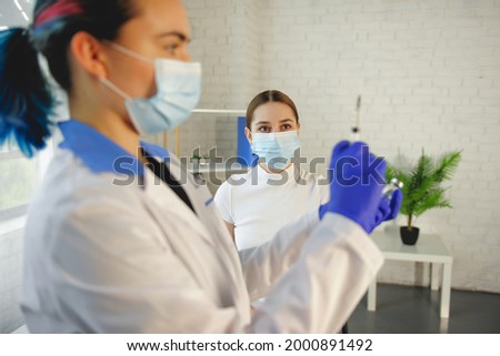 Caucasian doctor is preparing the vaccine for the patient at the medical center wearing masks