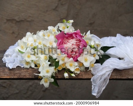 Delicate blooming bouquet of jasmine, pink peony with a white handkerchief on a gray background. Romantic picture with flowers jasminum and peonies for invitation design, greeting card, wallpaper