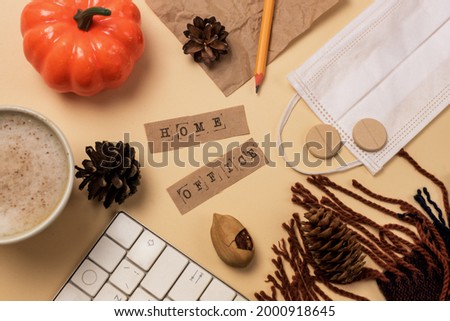 Workspace with Laptop or Keyboard Pencil Cozy and Warm Scarf Pumpkin Pine Cone and Face Mask and Pills Yellow Background Autumn Covid 19 Concept Lock Down or Home Office