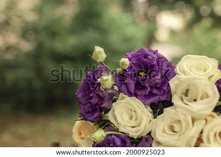 A bouquet of white roses lies on a wooden stump in the park.