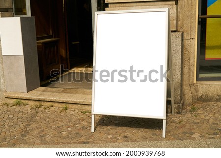 Billboard display mock-up template in front of entrance to shop or restaurant in a city
