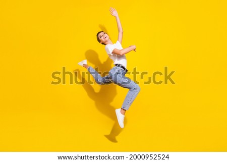 Full length profile side photo of young girl happy positive smile gymnastics jump sporty isolated over yellow color background