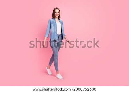 Full length body size photo girl smiling confident wearing stylish outfit walking forward isolated pastel pink color background Royalty-Free Stock Photo #2000952680