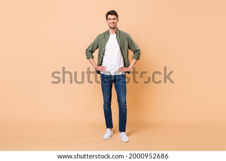 Photo of handsome pretty young gentleman wear khaki shirt walking arms waist smiling isolated beige color background Royalty-Free Stock Photo #2000952686