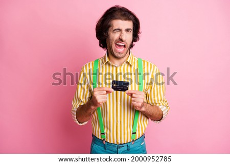 Photo of young handsome attractive male hold credit card blink wink eye wear suspenders isolated on pink color background