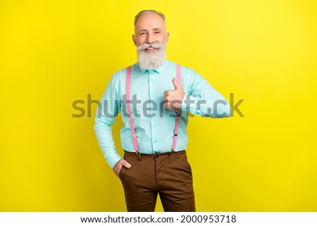 Photo of optimistic mature man show thumb up wear blue shirt isolated on vivid yellow color background