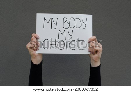 Female hands holding a protest a sign reading My Body My Choice Female right on legal abortion. Human rights freedom