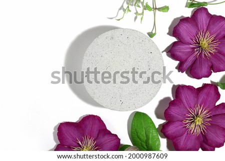 A podium made of concrete with pink clematis flowers, for the presentation of packaging and cosmetics, top view, on a white background. Product display with white concrete texture, stone texture.