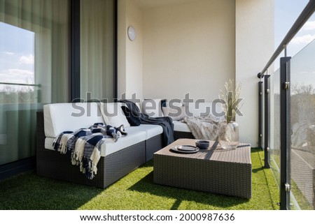 Nice balcony with rattan corner sofa and coffee table and synthetic grass on the floor Royalty-Free Stock Photo #2000987636