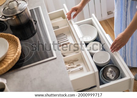 Top view modern housewife tidying up kitchen cupboard during general cleaning or tidying up. Female neatly placing dishware and cutlery in drawer of table. Storage organization Konmati method Royalty-Free Stock Photo #2000999717